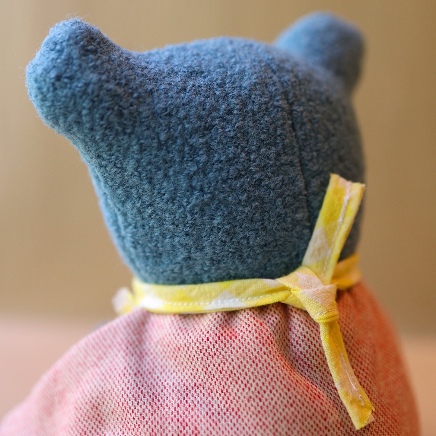Berry the Floppy Teddy in peach pajamas and wool boucle back of head