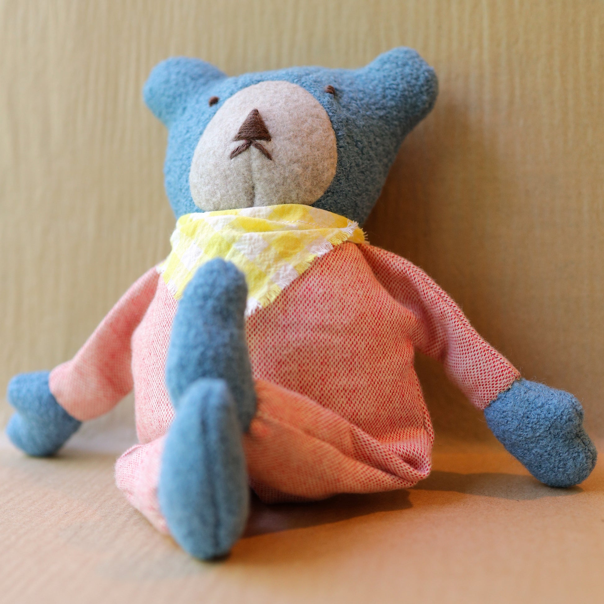 Berry the Floppy Teddy in peach pajamas and wool boucle crossed legs