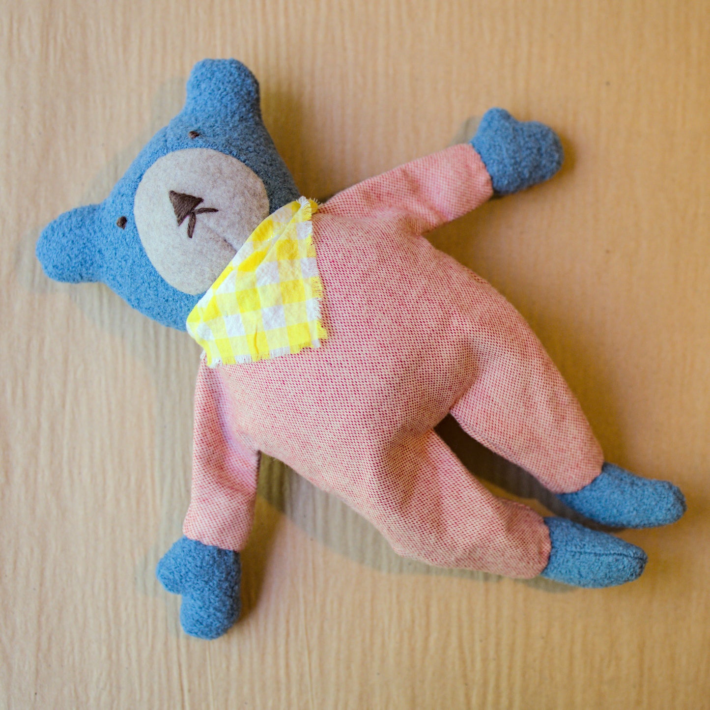 Berry the Floppy Teddy in peach pajamas and wool boucle laying down
