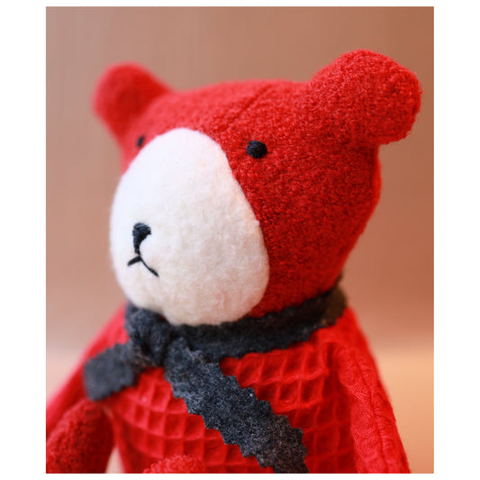 portrait of berry the floppy teddy in scarlet red with a white nose and grey scarf, side profile