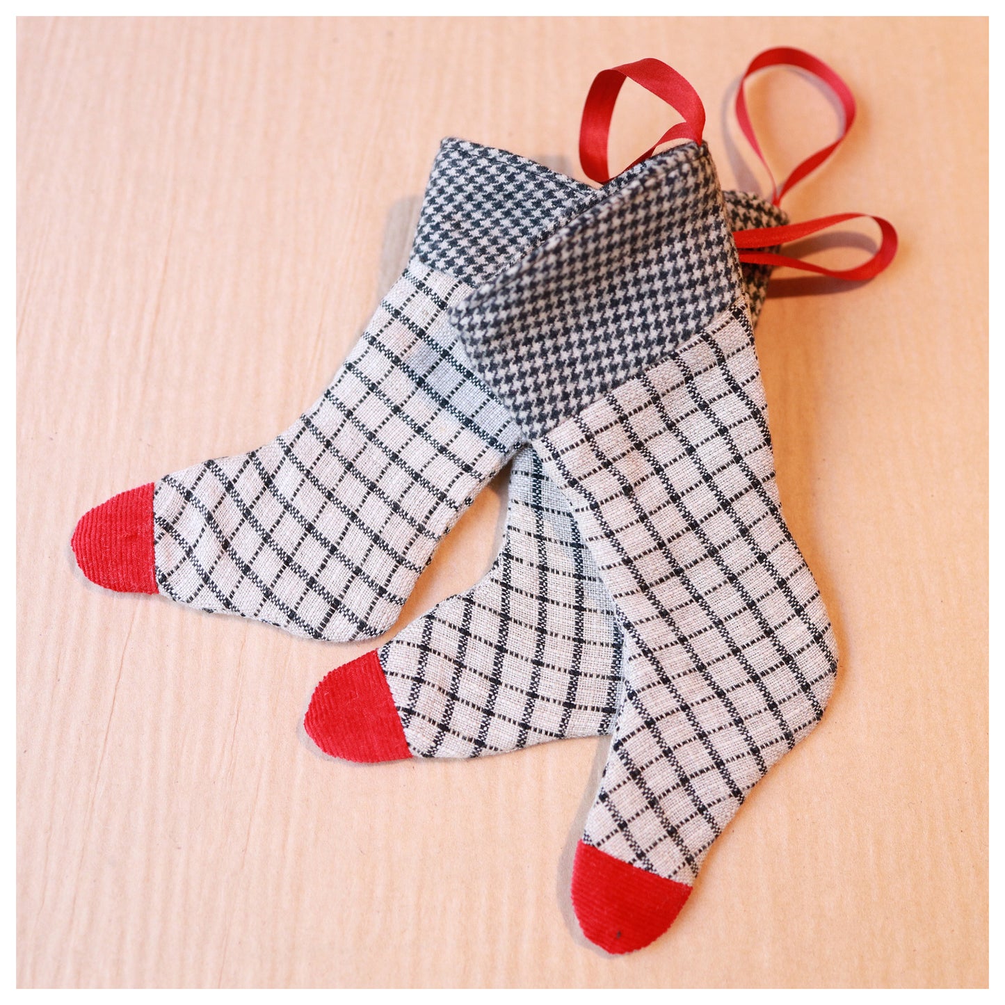 Plaid miniature stockings with red accents and silk hanging loop on brown background