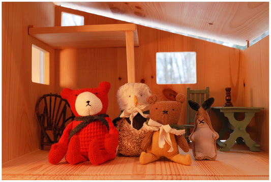 Modern pine dollhouse with toys lined up inside. Teddy bear, owl, mouse and bunny.