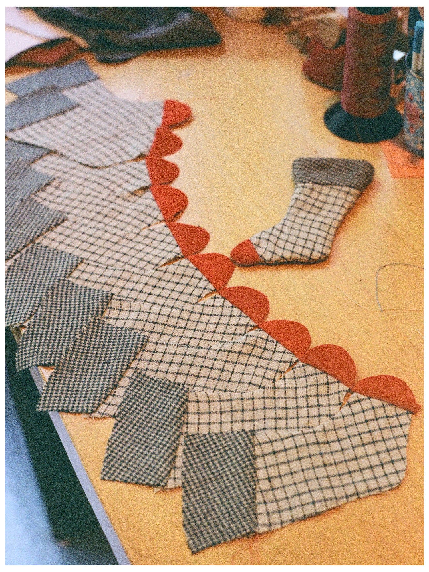 Fabric pieces for a mini hristmas stocking with a checkered pattern on a wooden desk. 