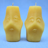 both sides of two faced beeswax candles showing two different hand sculpted faces 