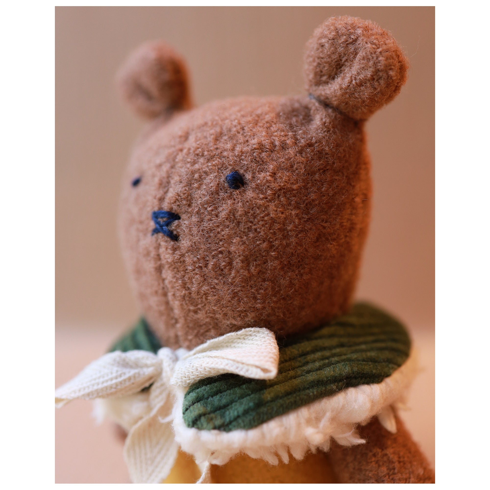 portrait of Brown toy mouse with a green collar and white bow on a beige background