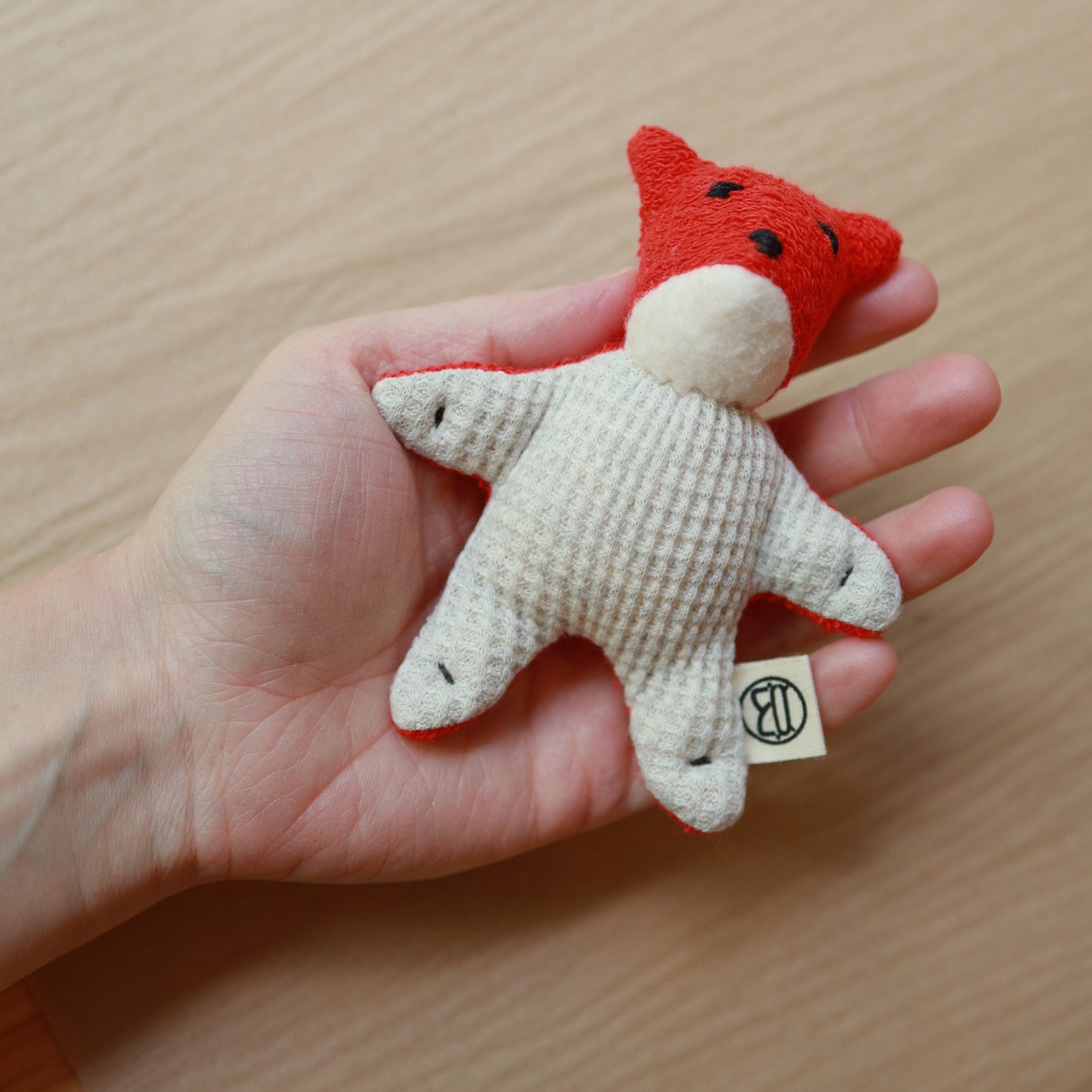 mini fox toy made from red terrycloth, fleece and light gray waffle fabric held in hand