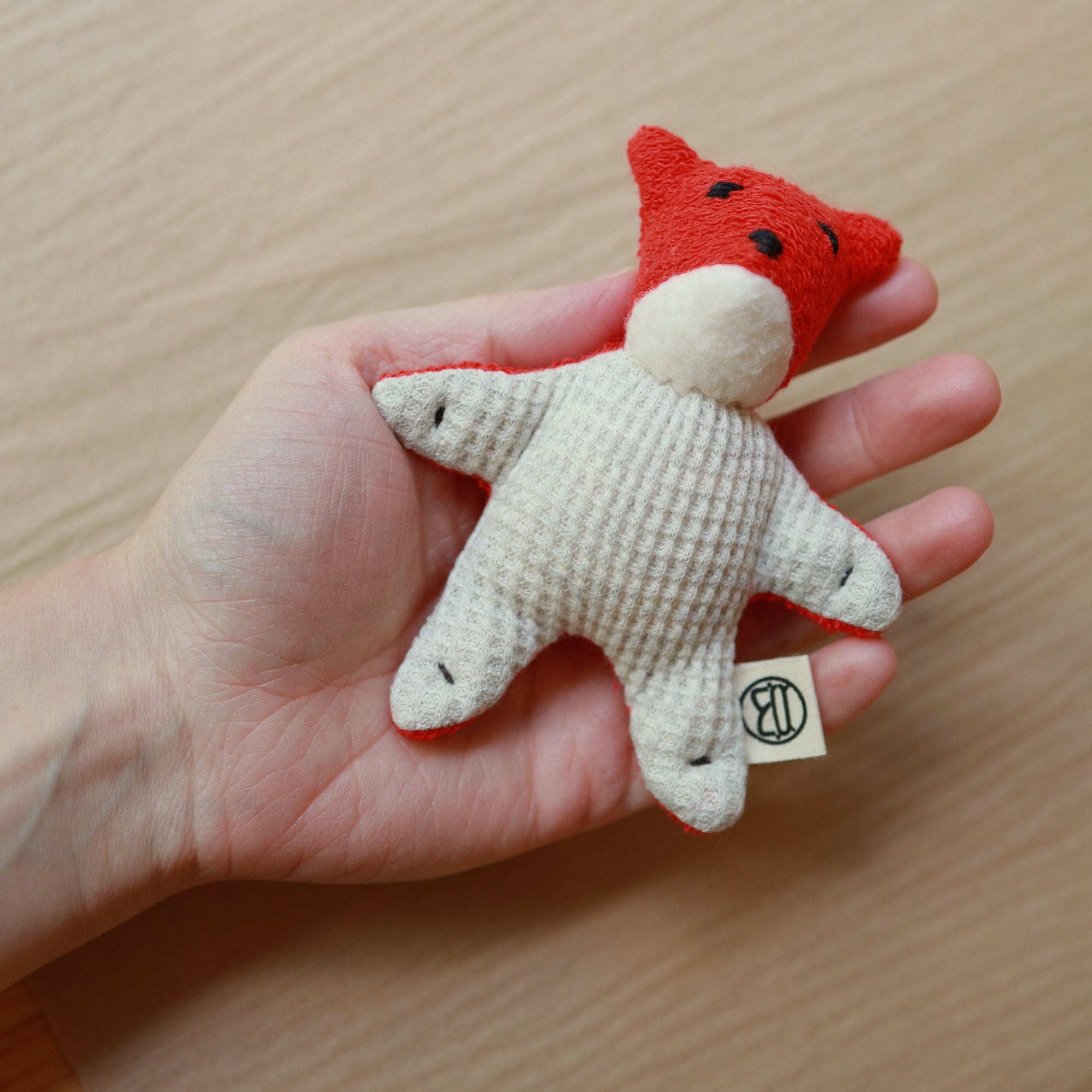 mini fox toy made from red terrycloth, fleece and light gray waffle fabric held in hand