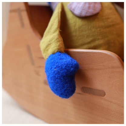 A close-up of a wooden rocking chair with a blur teddy bears paw resting on it