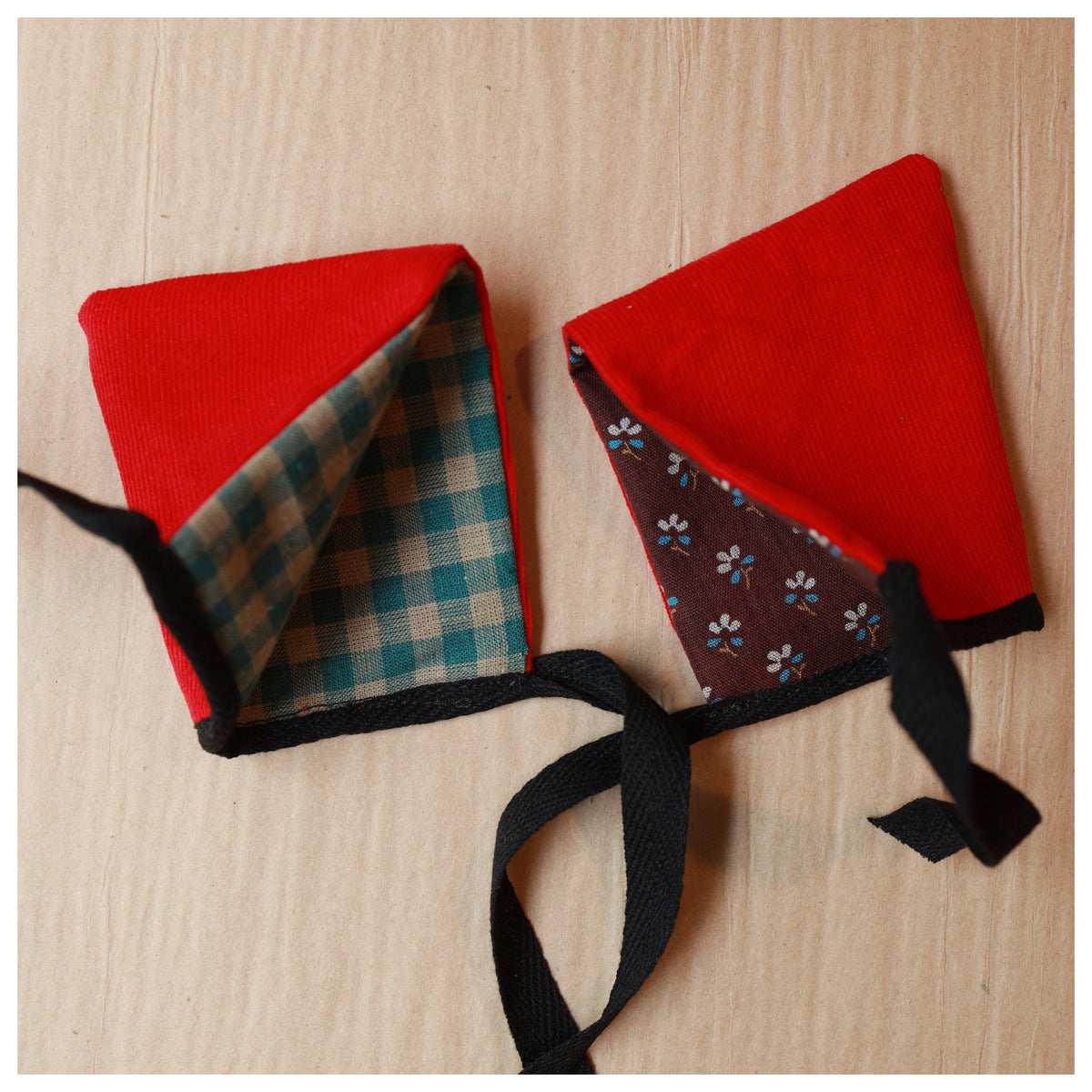 two red hoods for toys lined with checked linen and brown printed japanese cotton and with a black ribbon to tie it on