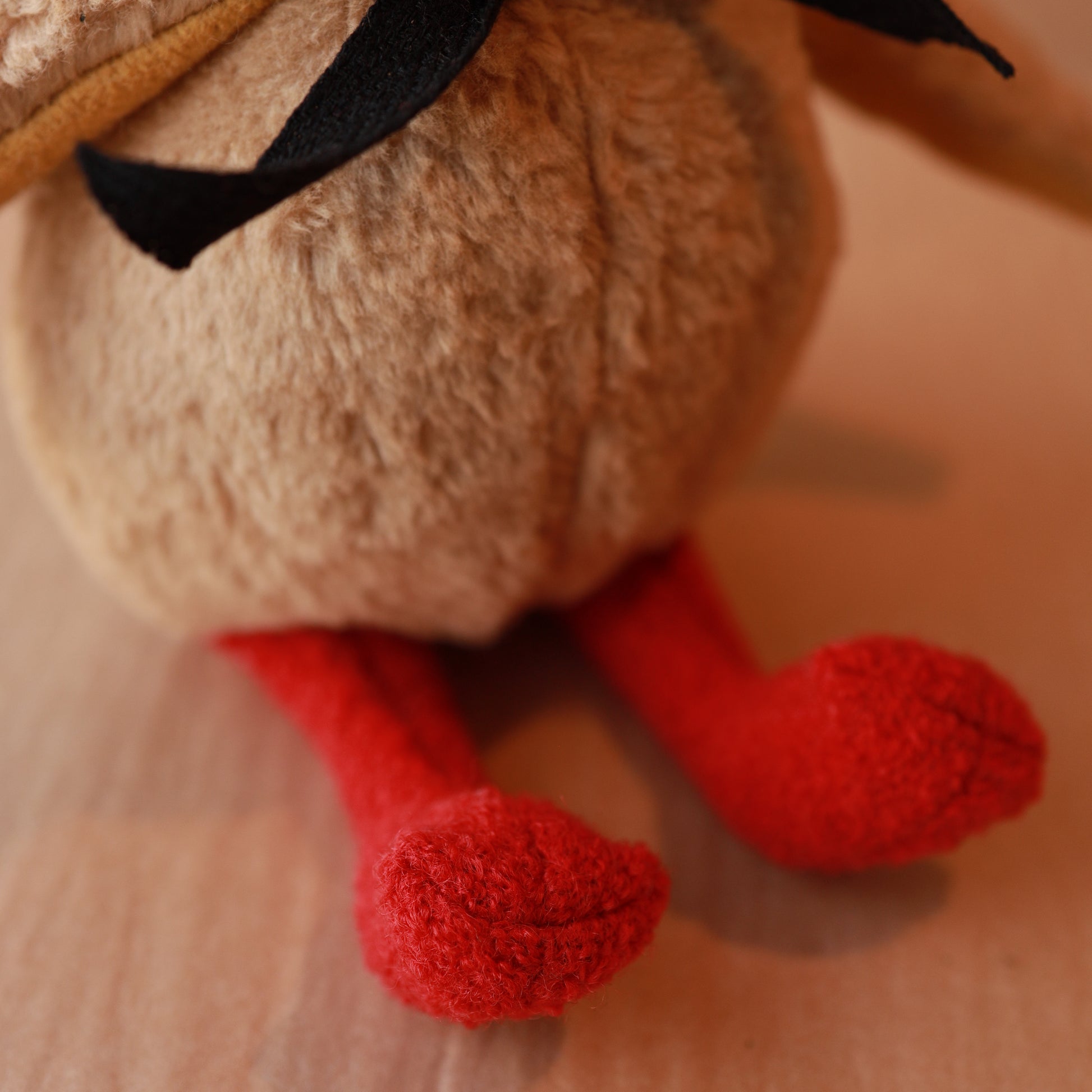 Close-up of a plush toy with red feet on a blurred background